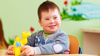 cute kid with down's syndrome playing in kindergarten